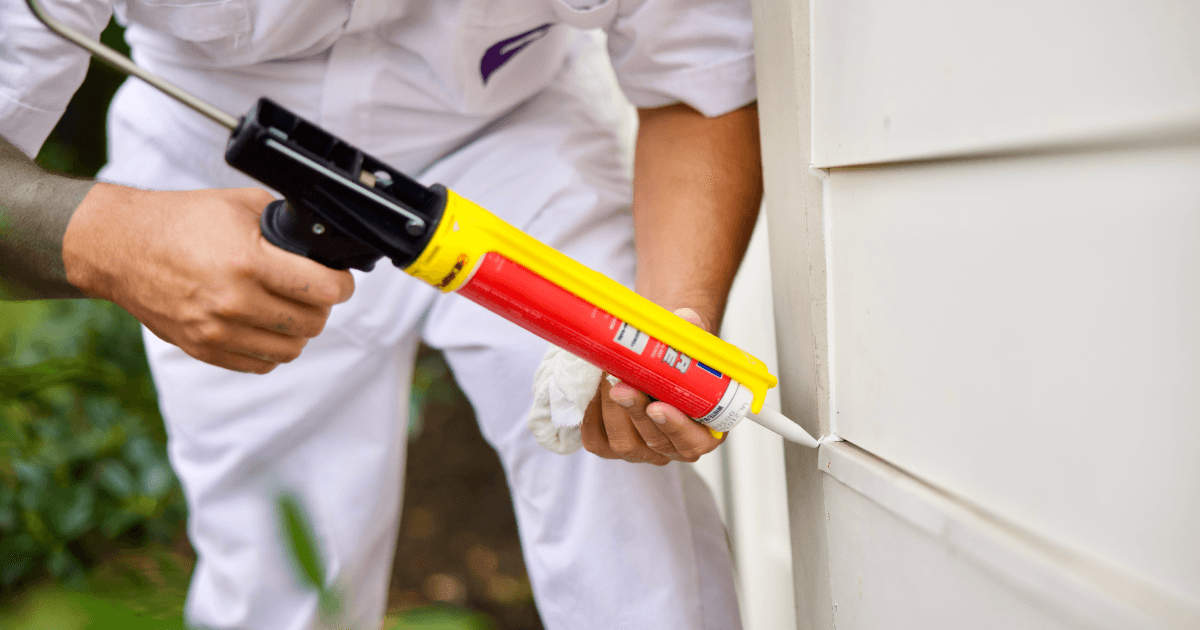Man caulking exterior of home