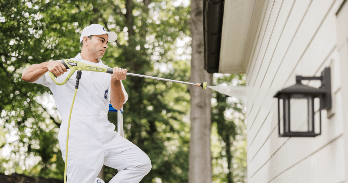 Man power washing exterior of house
