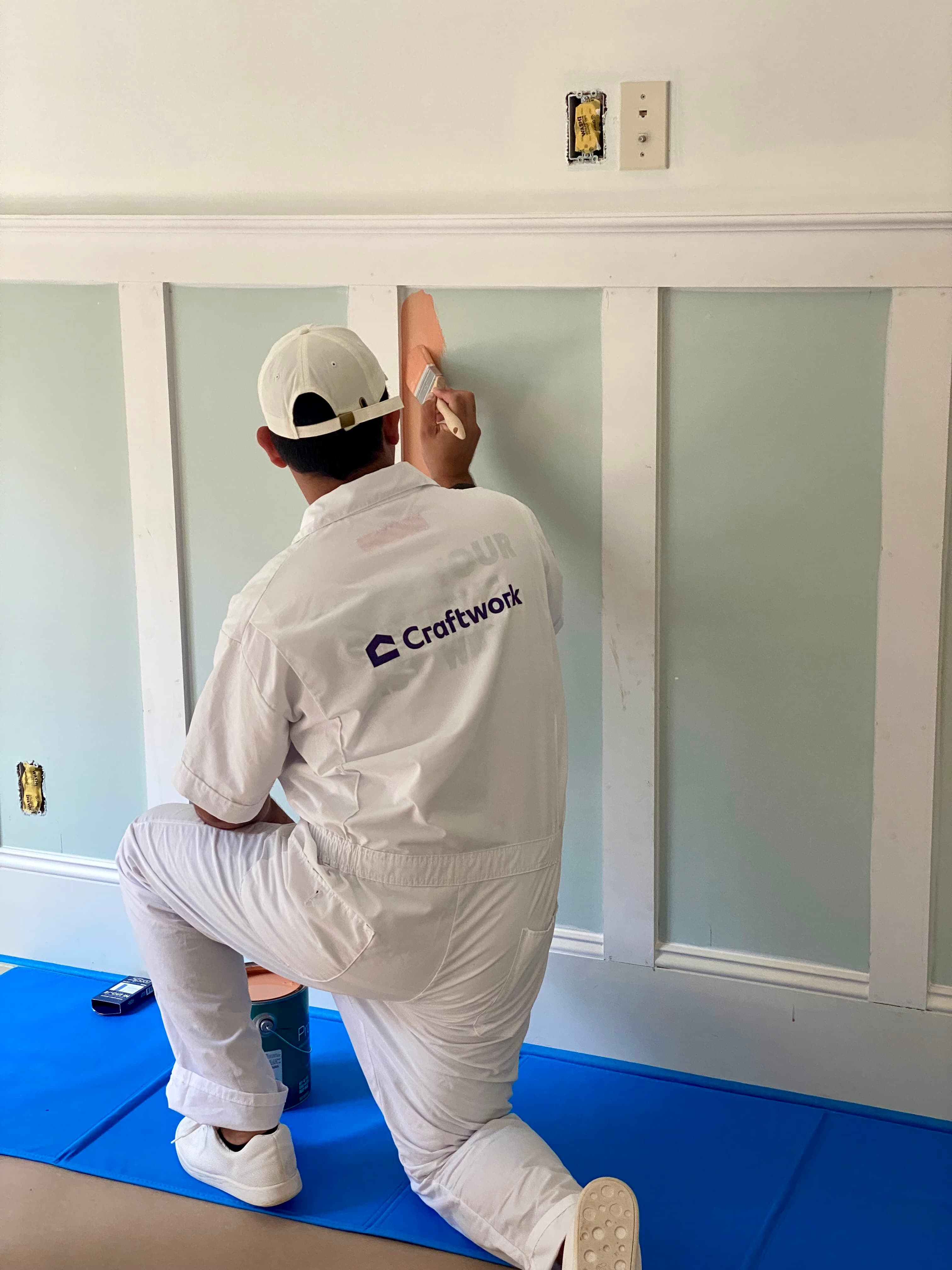 Craftwork home painter adding orange paint to a wall with a brush.